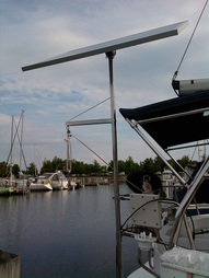 rigid marine solar panel mounted top of pole on sailboat with outboard motor lifting crane accessory attached